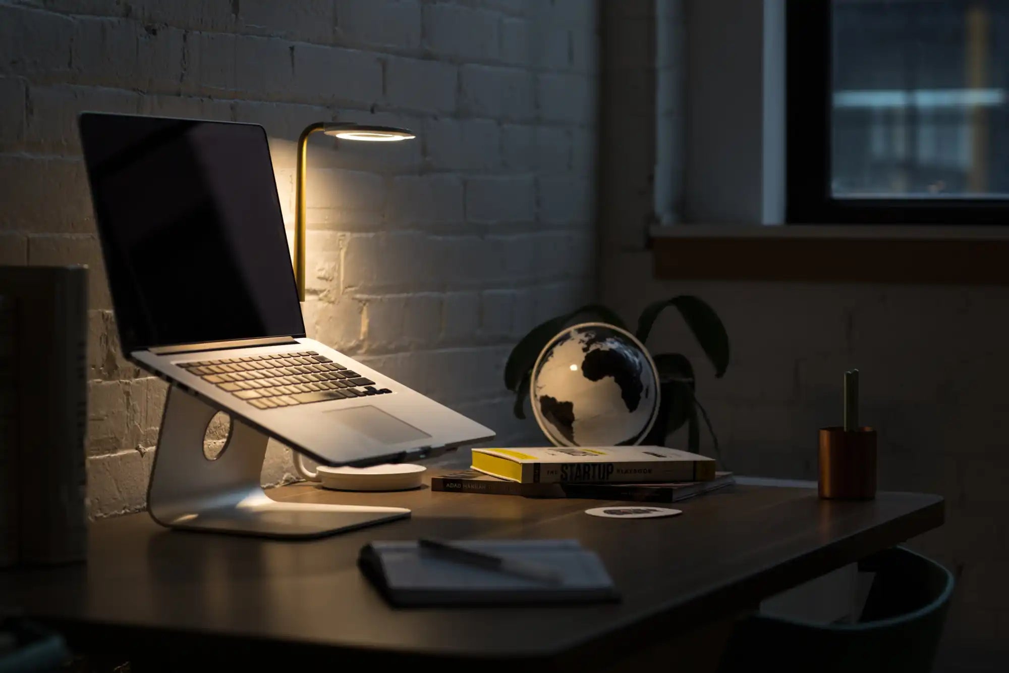 Laptop on a stand with its screen illuminated in a dimly lit setting.